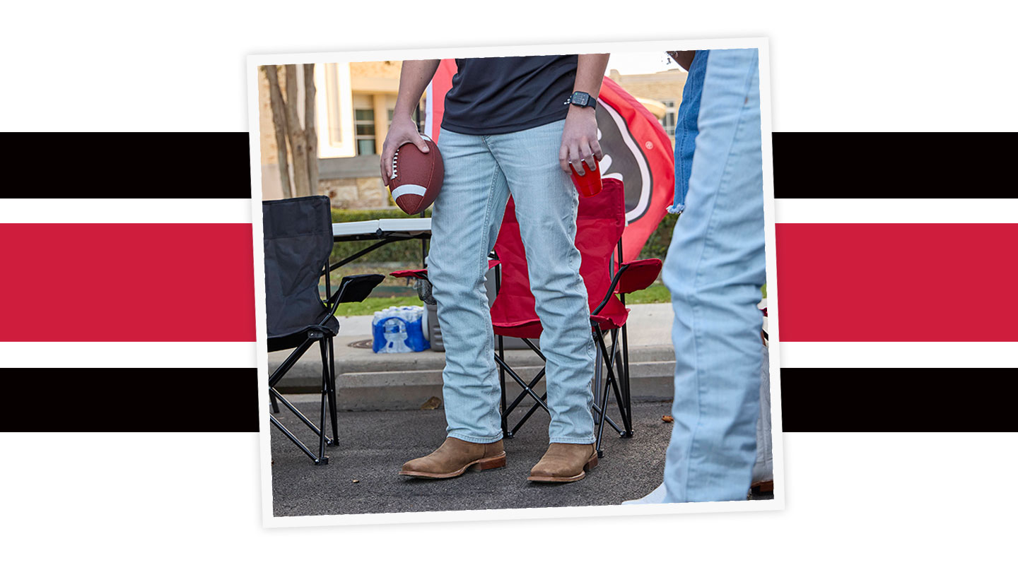 A Man wearing Justin Western boots while holding a football.